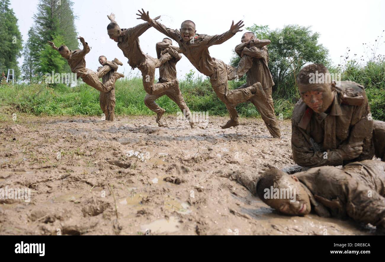 MUDDY COPS These are no bog-standard training methods. Rookie police wannabes are literally dragged into the mire by their tough, non nonsense boot camp drill sergeant as they slog through the swampy terrain. Each participant at the Police Training College in Chuzhou City, Anhui Province, China, aims to graduate from aspiring boys-in-blue aim to graduate to full-fledged copper . .  Stock Photo