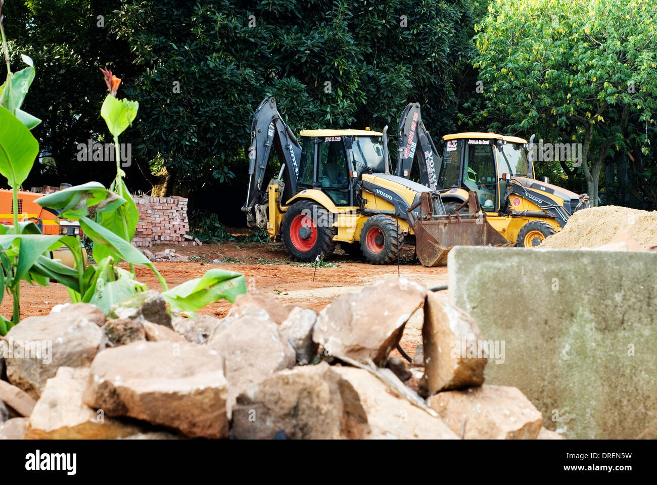 Two graders machines with bricks preparing the land for construction of home. Stock Photo
