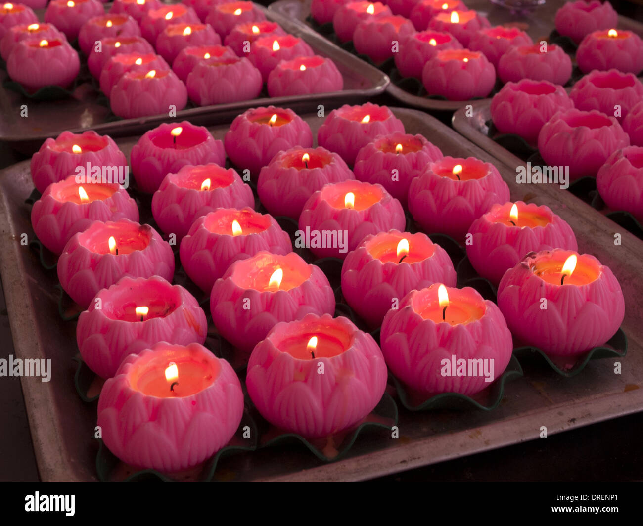 trays full of rows of pink flowershaped candles burn in a Chinese
