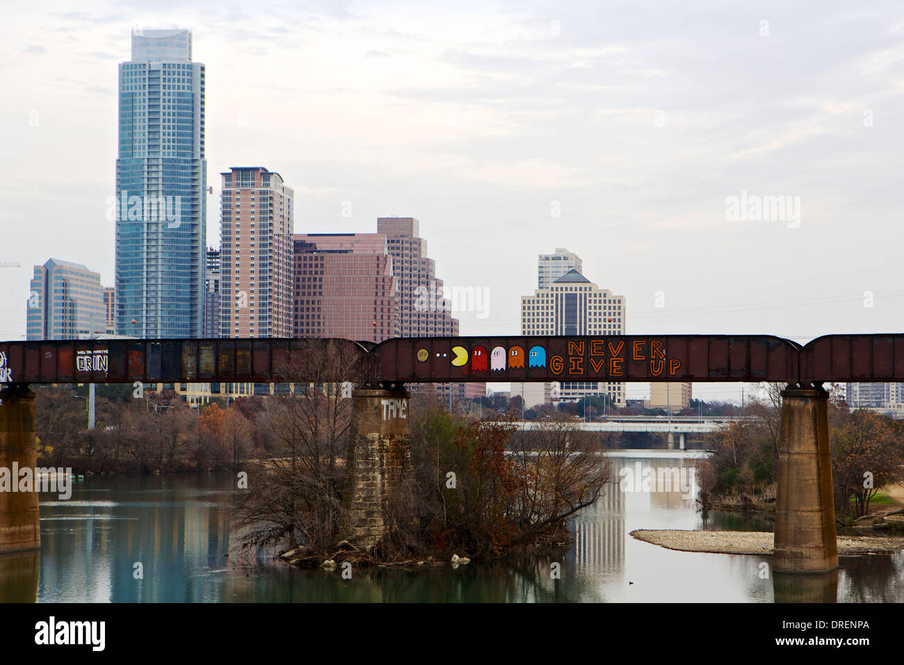 Graffiti covered railroad bridge over the Colorado river with the Austin skyline in the background Stock Photo