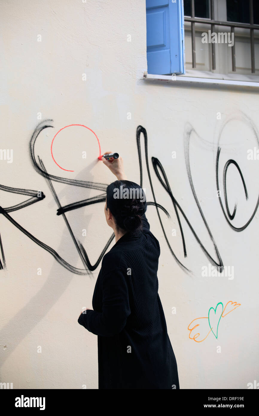 europe greece athens plaka a woman graffiti artist writing on a wall ...