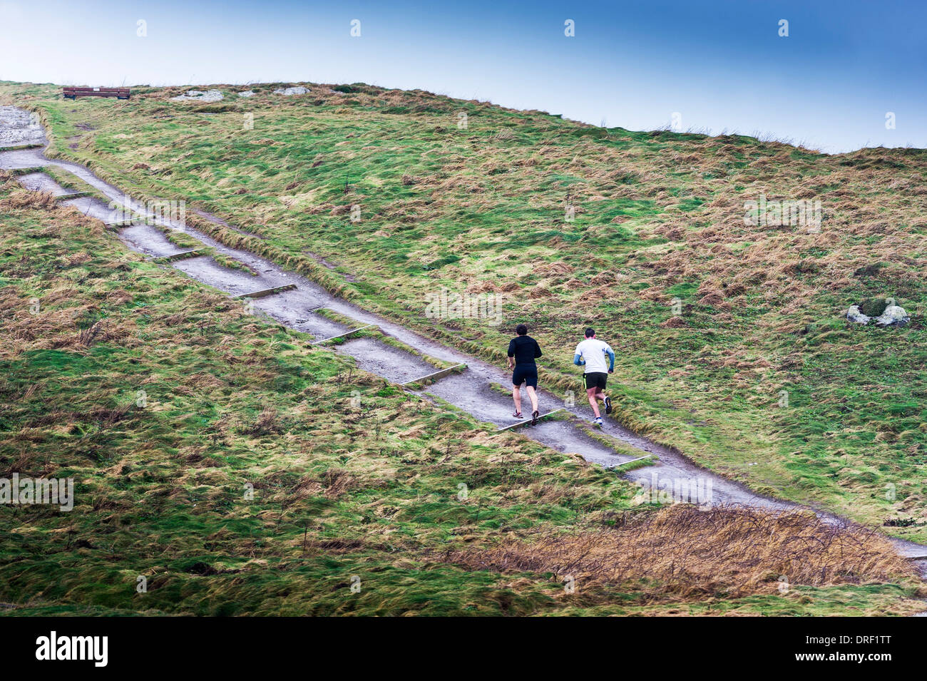 Two people running up a steep path. Stock Photo