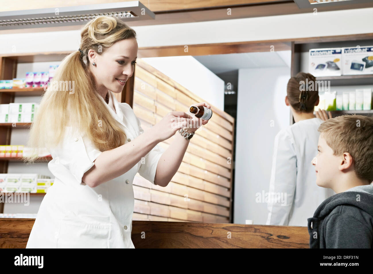 Female Pharmacist Giving Boy Cough Syrup, Munich, Bavaria, Germany