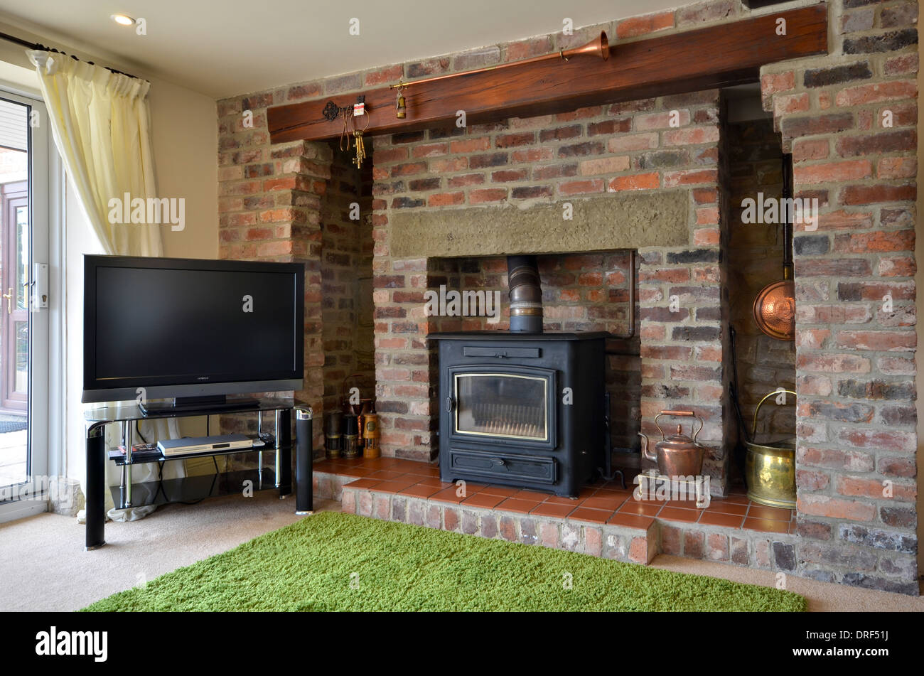 Brick fireplace with wood burning stove and flatscreen television Stock Photo