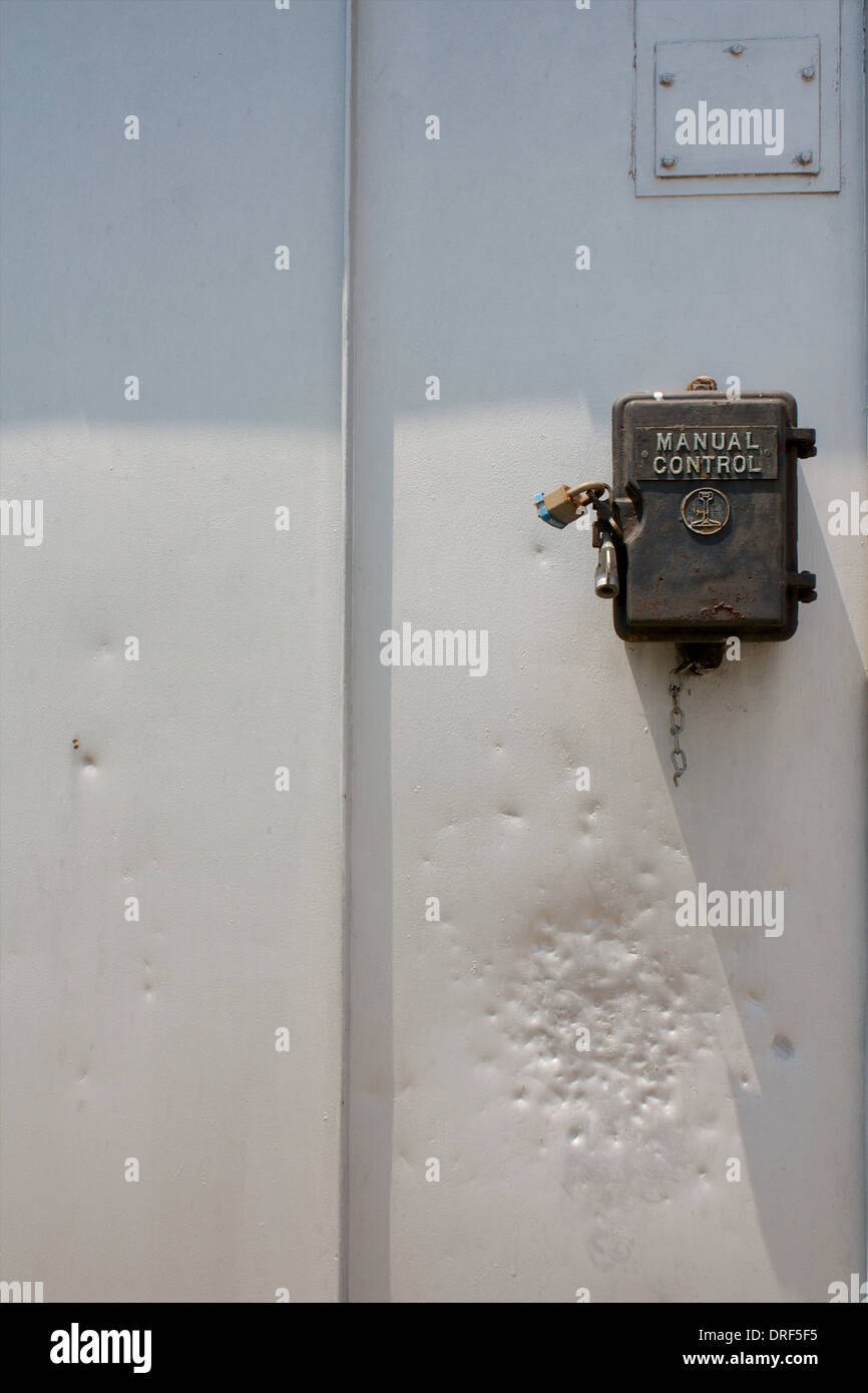 A locked manual control box on the side of a metal shed. Stock Photo