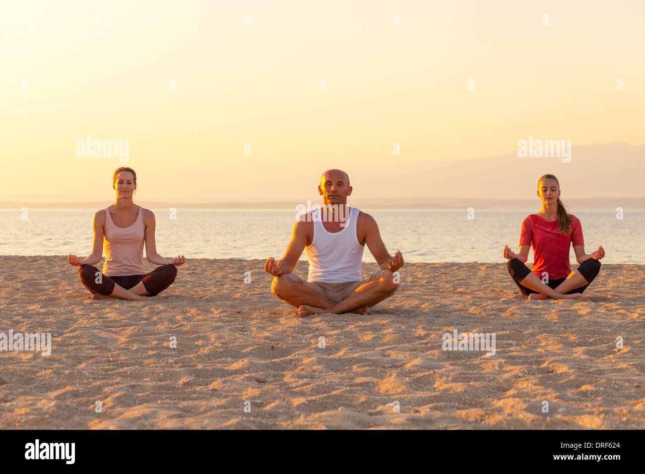 People practising yoga on beach, lotus pose Stock Photo - Alamy