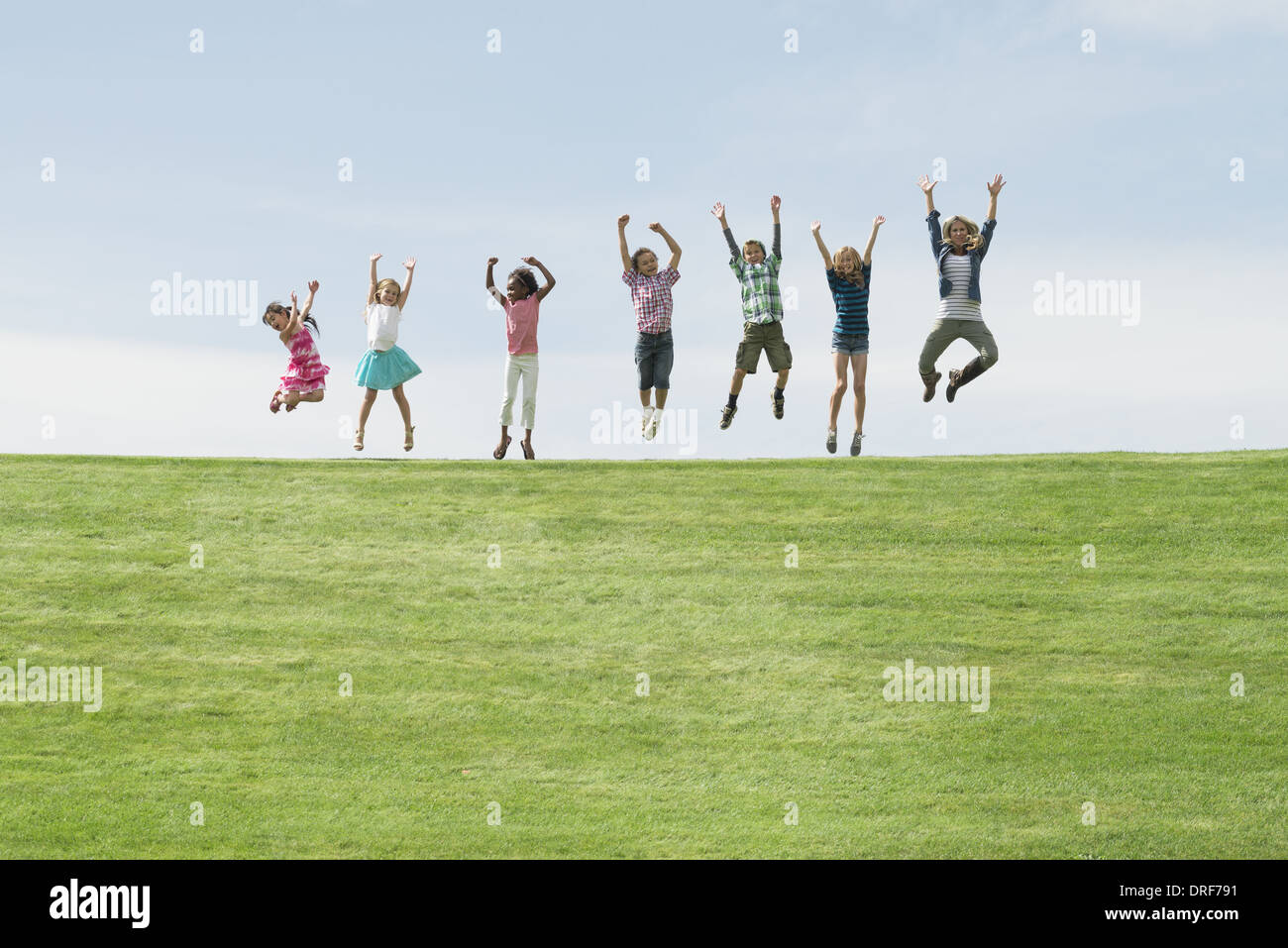 Utah USA group of children on top of hill in row leaping Stock Photo