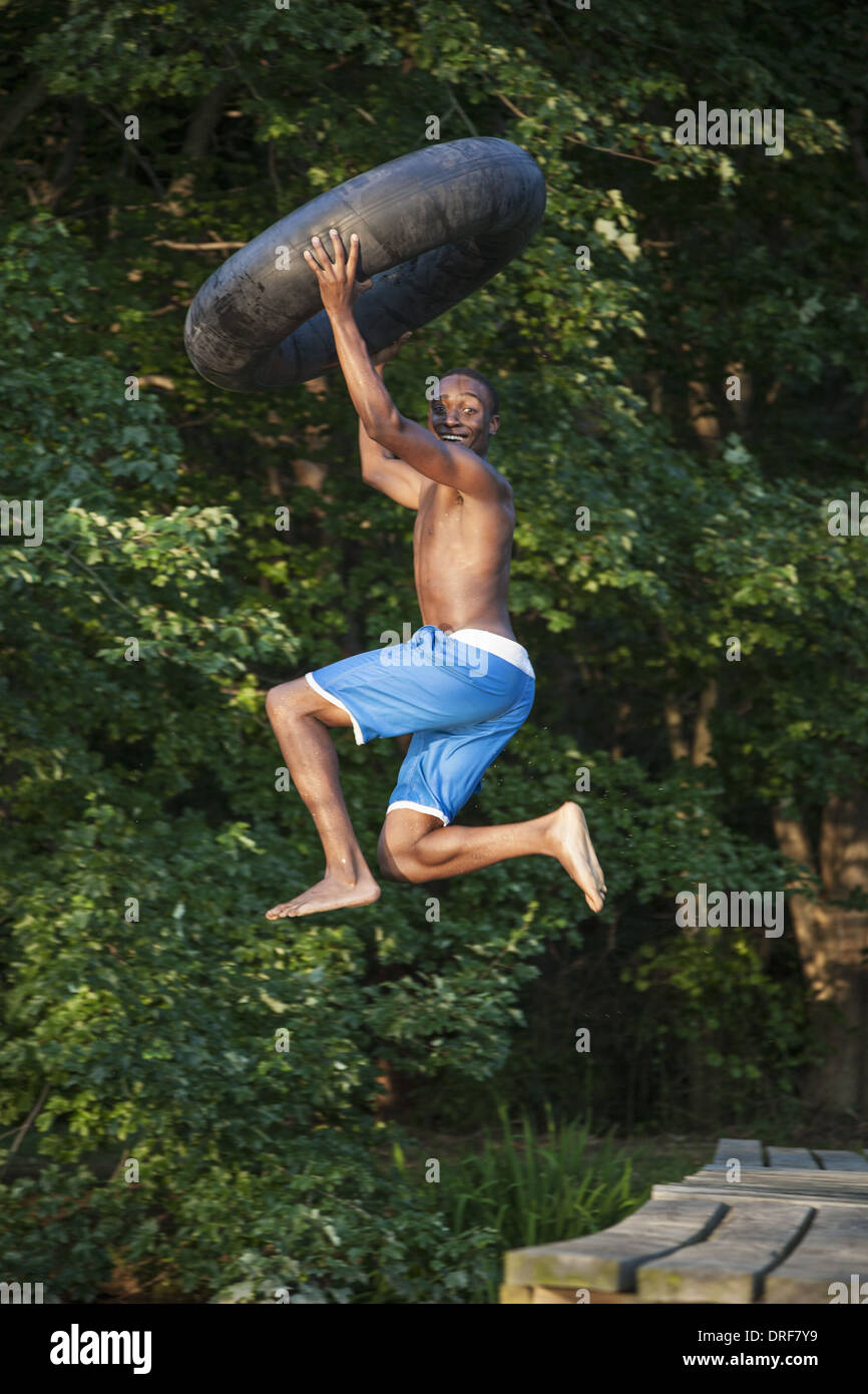Maryland USA person boy holding swim float tyre leaping lake Stock Photo