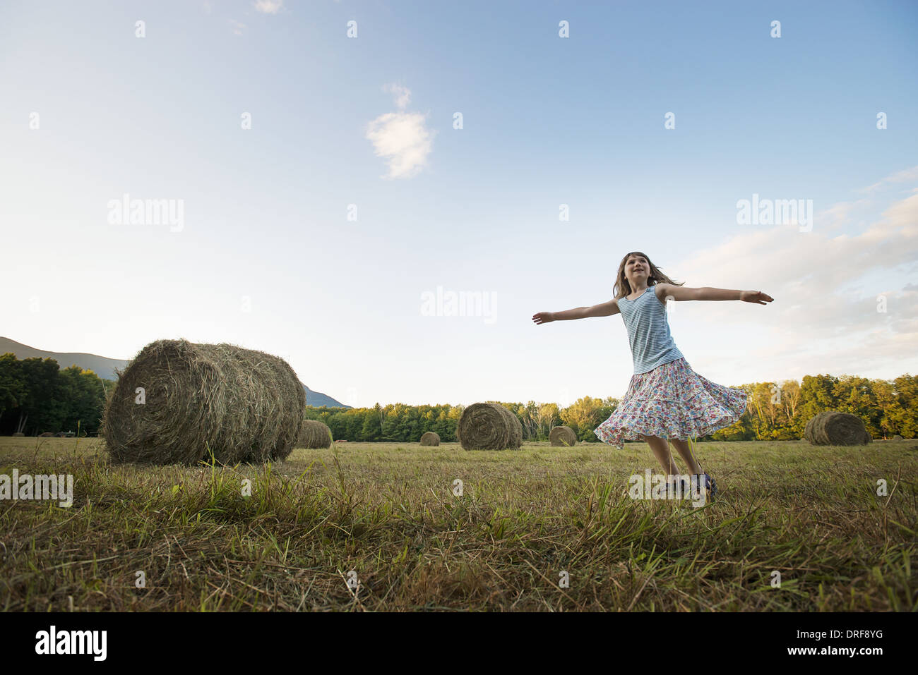 New York state USA field hay bales girl dancing arms outstretched Stock