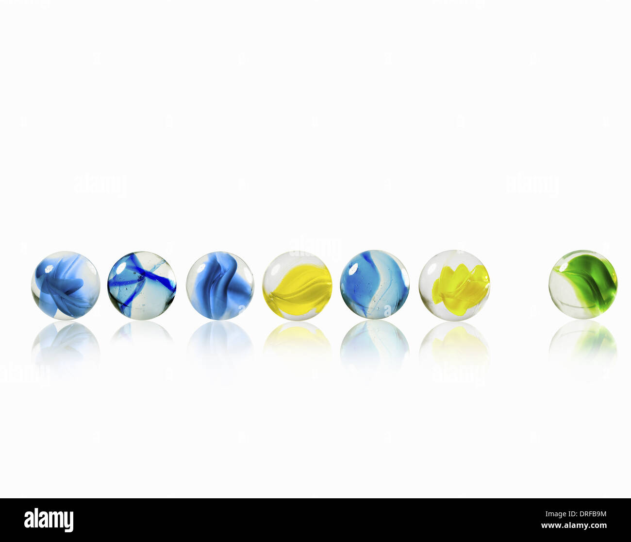 row of glass marbles one separated from the rest Stock Photo