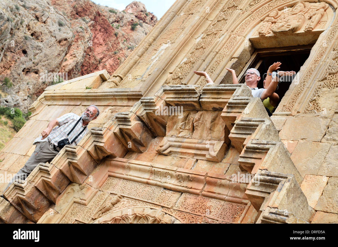 Tourists sit on stairs of Surb Astvatsatsin, the Holy Mother of God Church, Noravank, Armenia Stock Photo