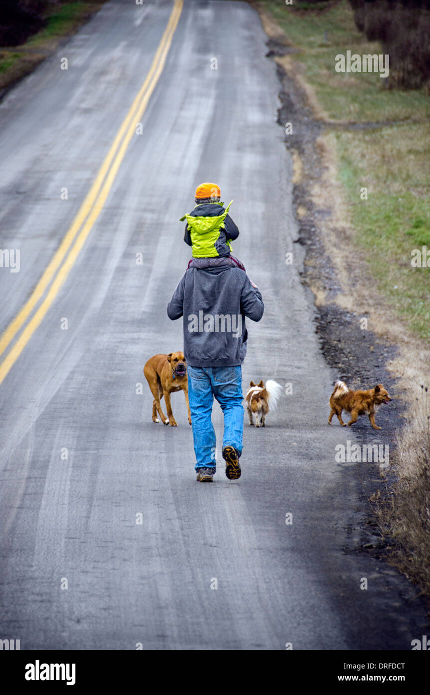father and son man carrying boy on shoulders walking on a road with