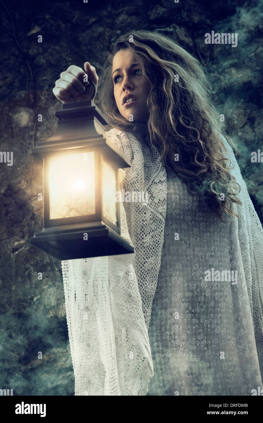 Woman with lantern standing in the dark Stock Photo