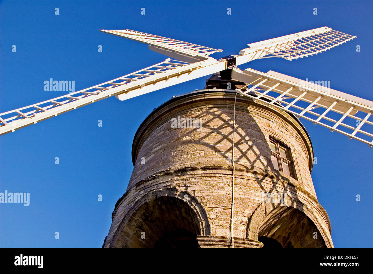 Chesterton Windmill in central Warwickshire, with unique stone arch undercroft and white lattice timber sails with a blue sky. Stock Photo