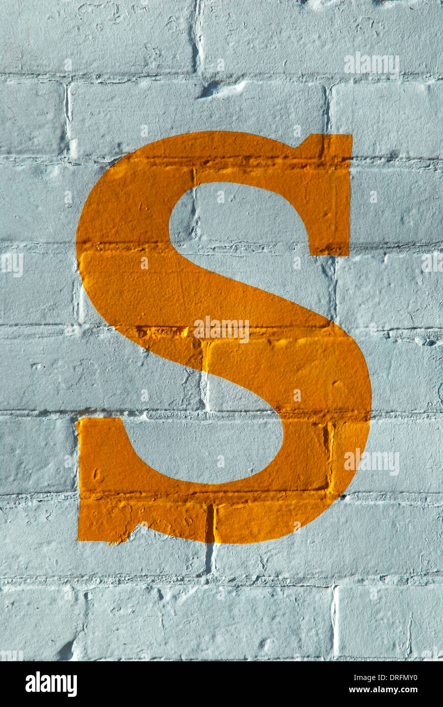 White painted brick wall with red and yellow letters painted on