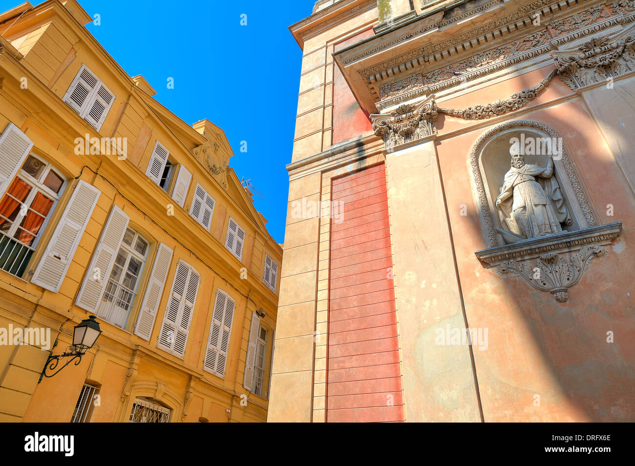 Fragment of catholic church and yellow building under blue sky in town of Menton, France. Stock Photo
