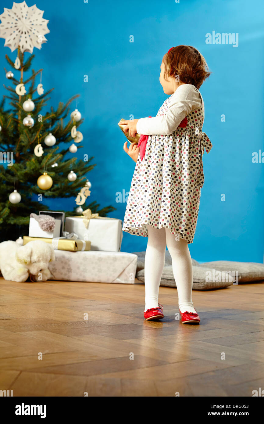 Little girl holding Christmas present, looking over shoulder, Munich, Bavaria, Germany Stock Photo