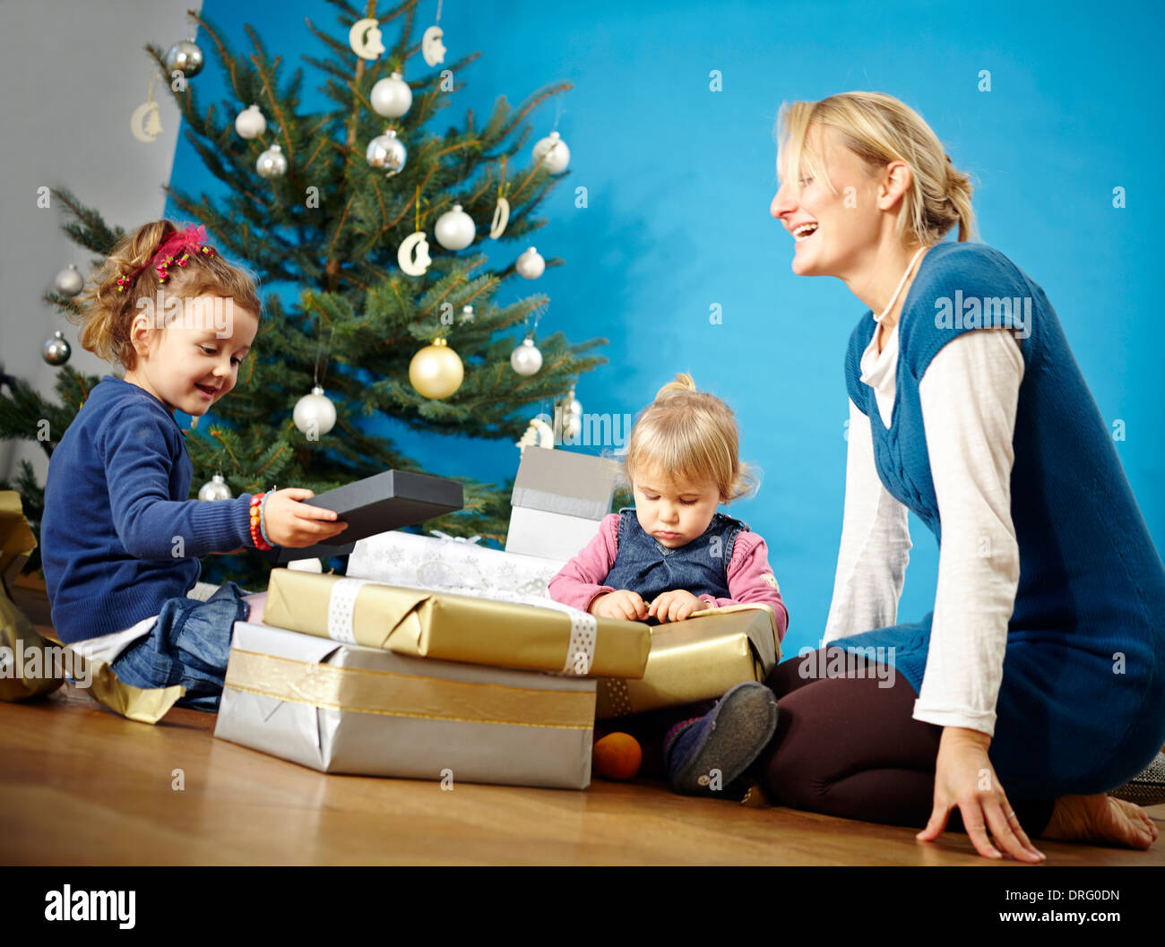Mother and two girls unwrapping Christmas presents, Munich, Bavaria, Germany Stock Photo