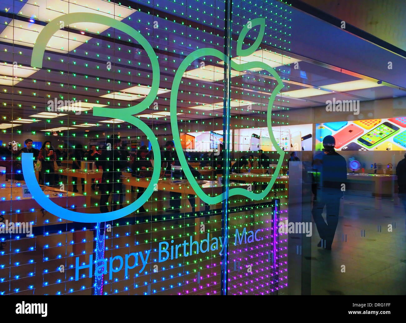 Garden City, New York, U.S. January 24, 2014. 30 years after Steve Jobs introduced the Macintosh computer to the public, this Apple store front window has colorful animated electric display with '30 Happy Birthday Mac' and the Apple logo is used for the 0 (zero) in the number 30 (thirty). Photo taken with an Apple iPhone 5S. Credit:  Ann E Parry/Alamy Live News Stock Photo