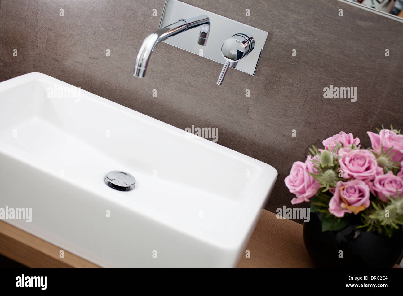 Bathroom with square washbasin and chromed tap. Roses on the side Stock Photo