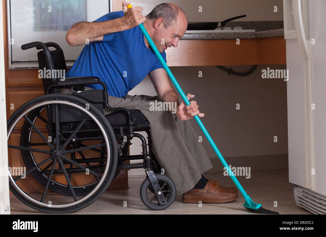 Man with Friedreich's Ataxia and deformed hands cleaning his house from his  wheelchair with a broom Stock Photo - Alamy
