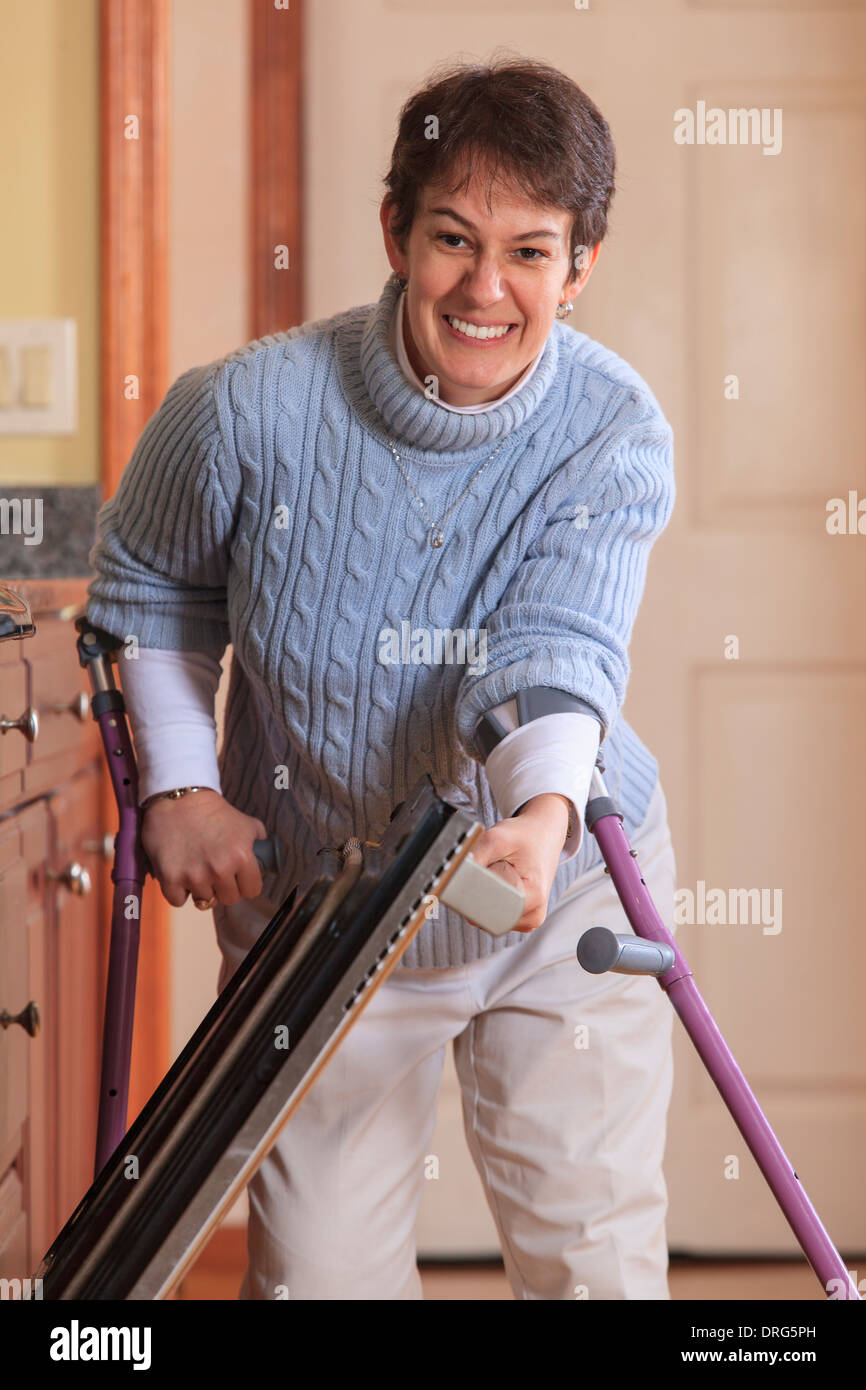 Woman with Cerebral Palsy using crutches and opening her dishwasher in