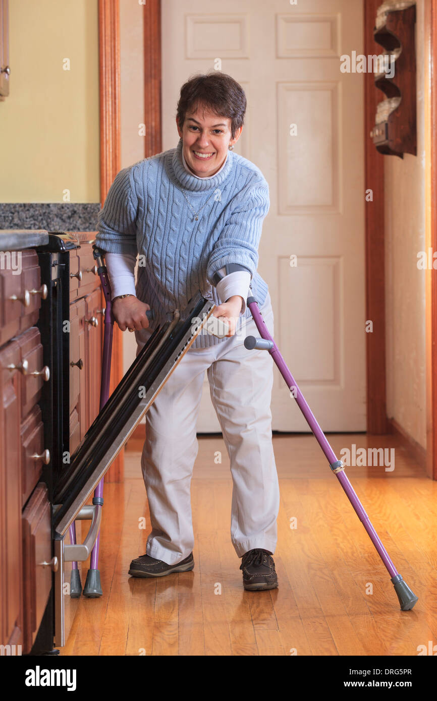 Woman with Cerebral Palsy using crutches and opening her dishwasher