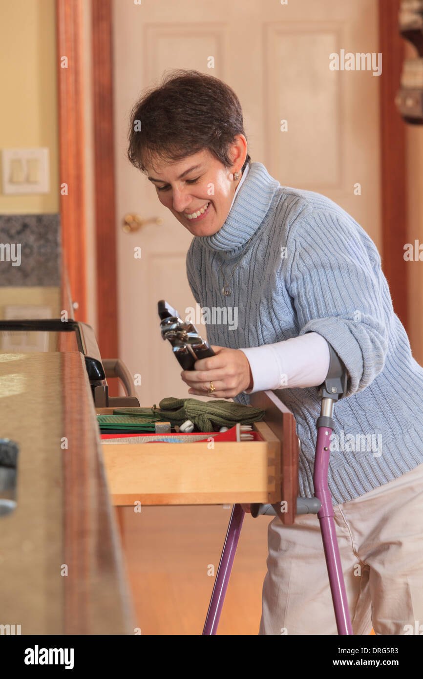 Woman with Cerebral Palsy using crutches and opening a drawer in her