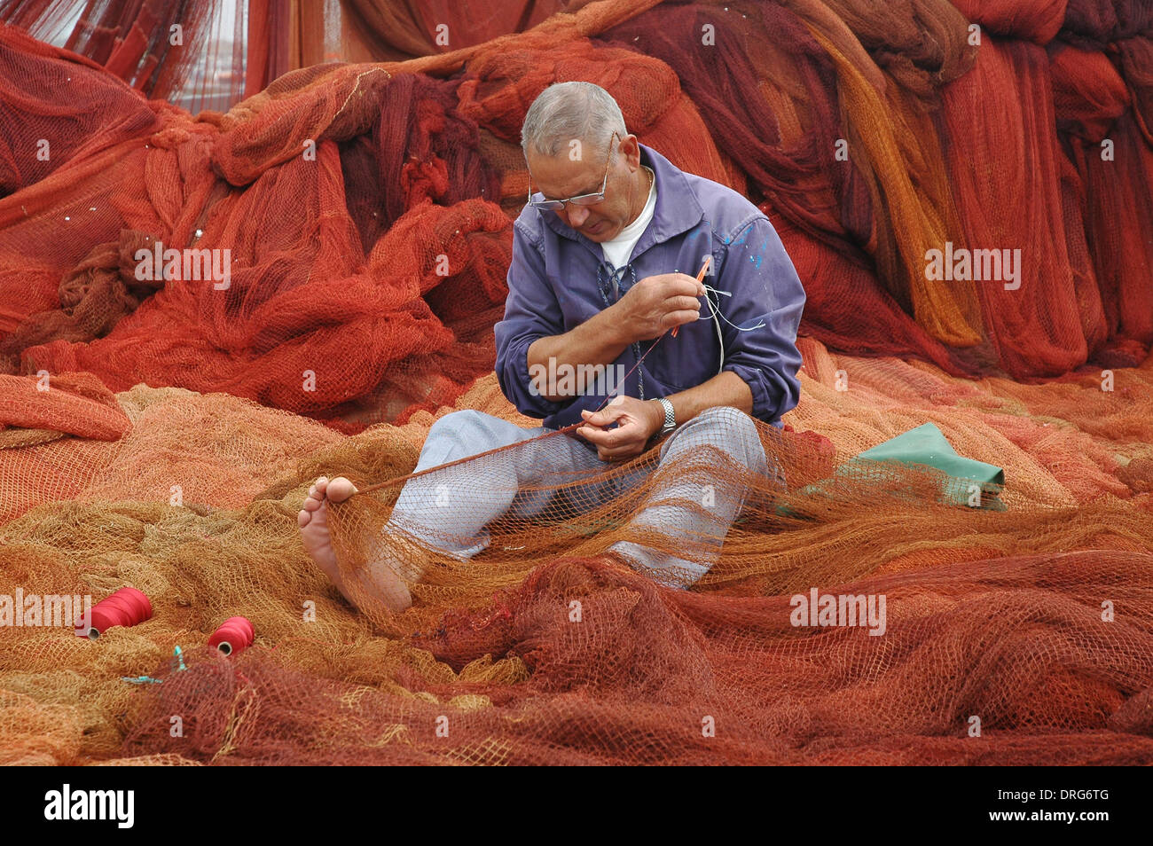 A fisherman mending fishing nets in Peniche harbor located in Oeste  Subregion in formerly Estremadura Province Portugal Stock Photo - Alamy