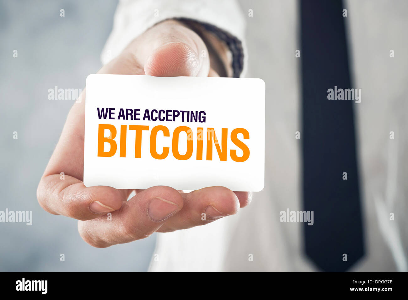 Businessman holding card with title WE ARE ACCEPTING BITCOINS. Selectve focus on card and fingers. Stock Photo