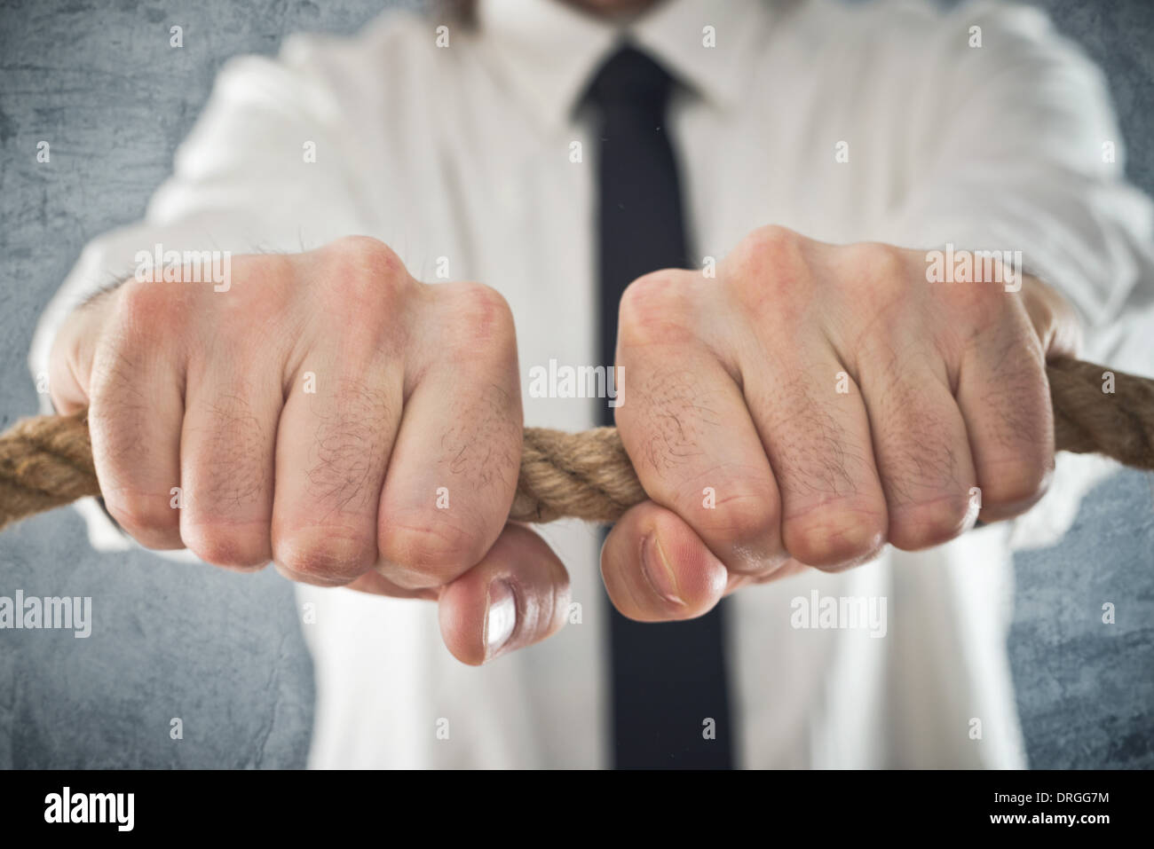 Businessman holding tight to a rope. Concept of business problems, difficult business situation. Stock Photo