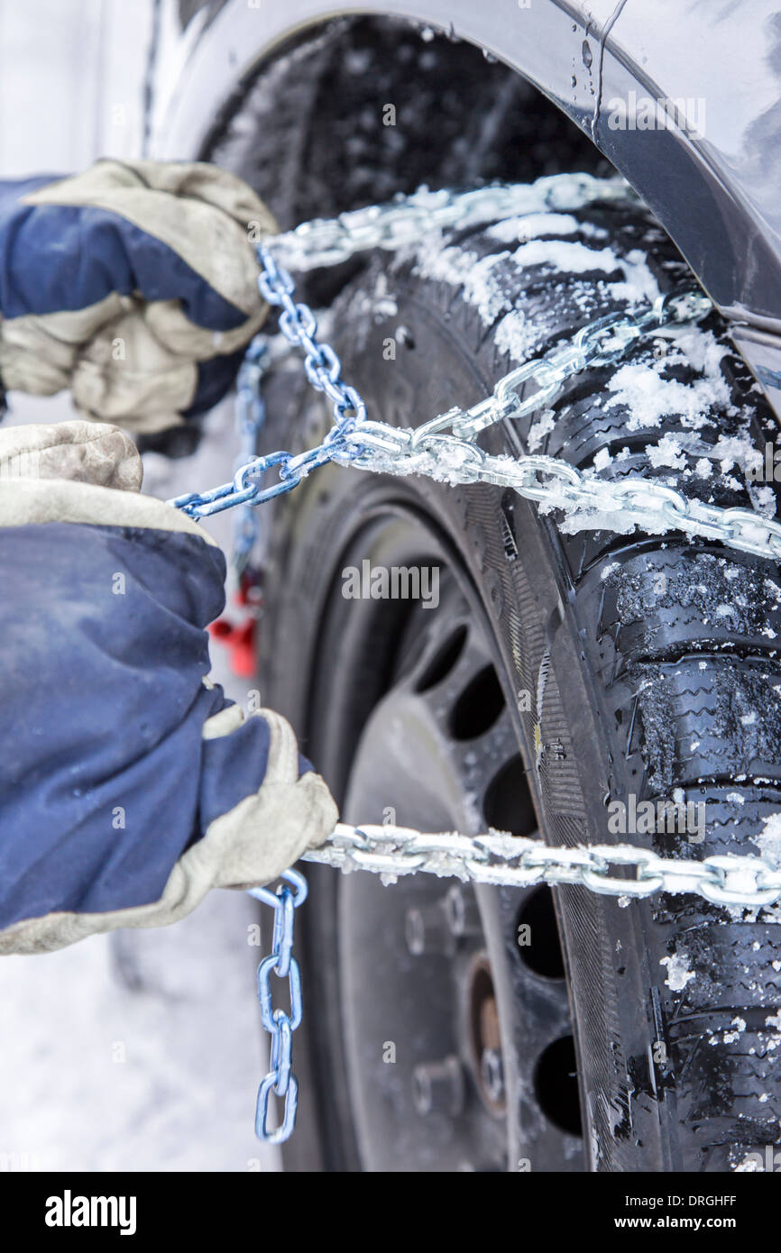 Car driver mounts snow chains on the tire of his car Stock Photo Alamy