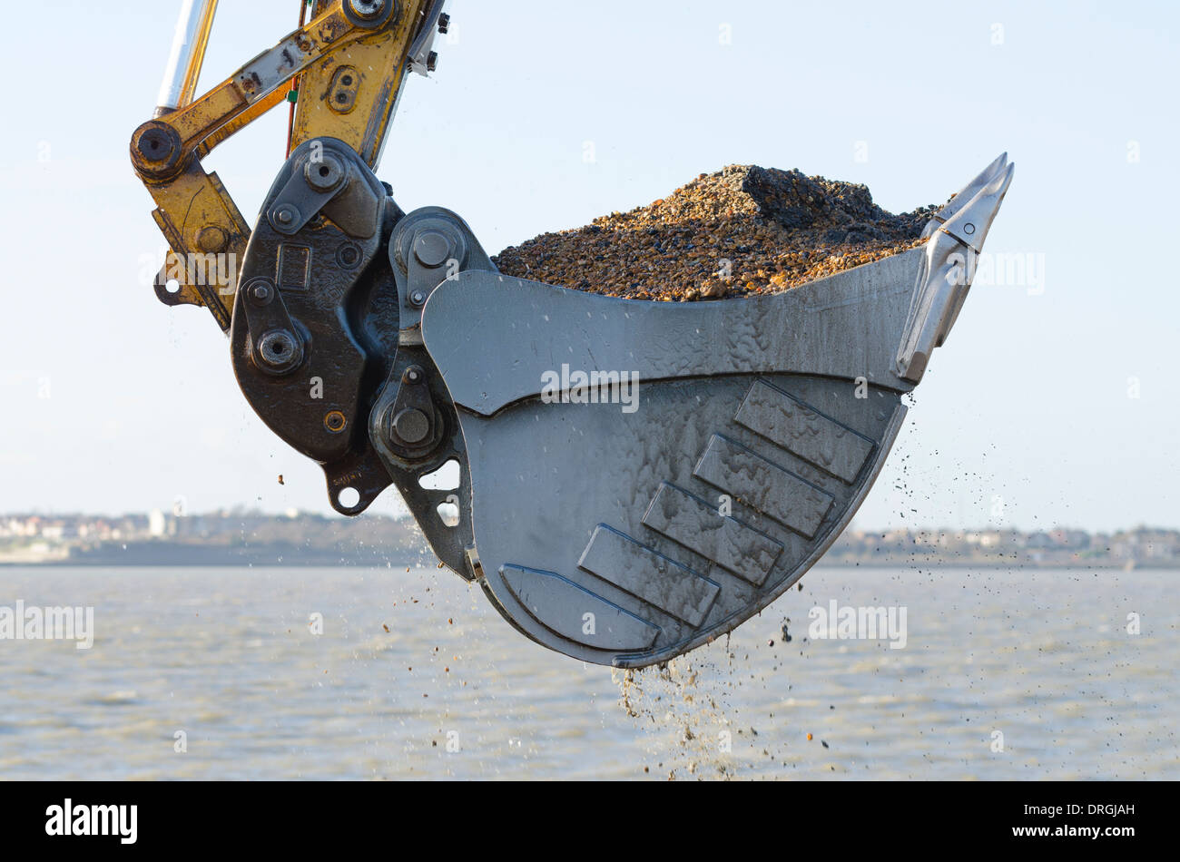 Excavator bucket dredging sand and gravel from the seafront Stock Photo