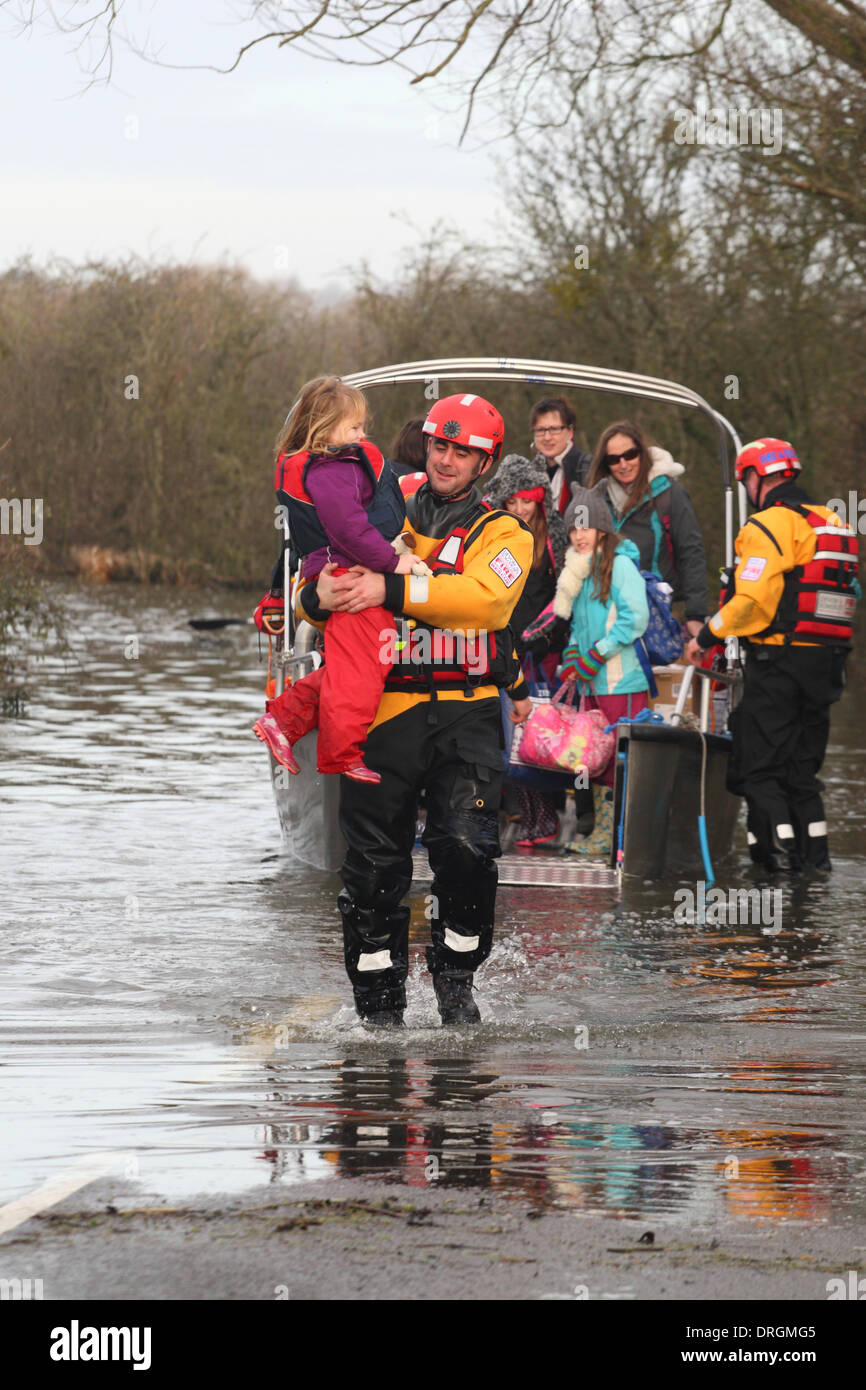 Muchelney, Somerset, UK. 25th Jan, 2014. A fireman from Devon & Somerset Fire and Rescue service carries a young girl from the humanitarian ferry boat back to dry land in Muchelney. The village has been cut off since early January 2104. Stock Photo