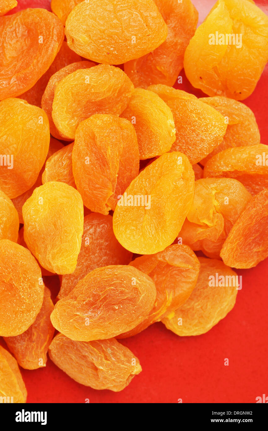 Heap of sweet dried apricot fruits on red plate, colorful food