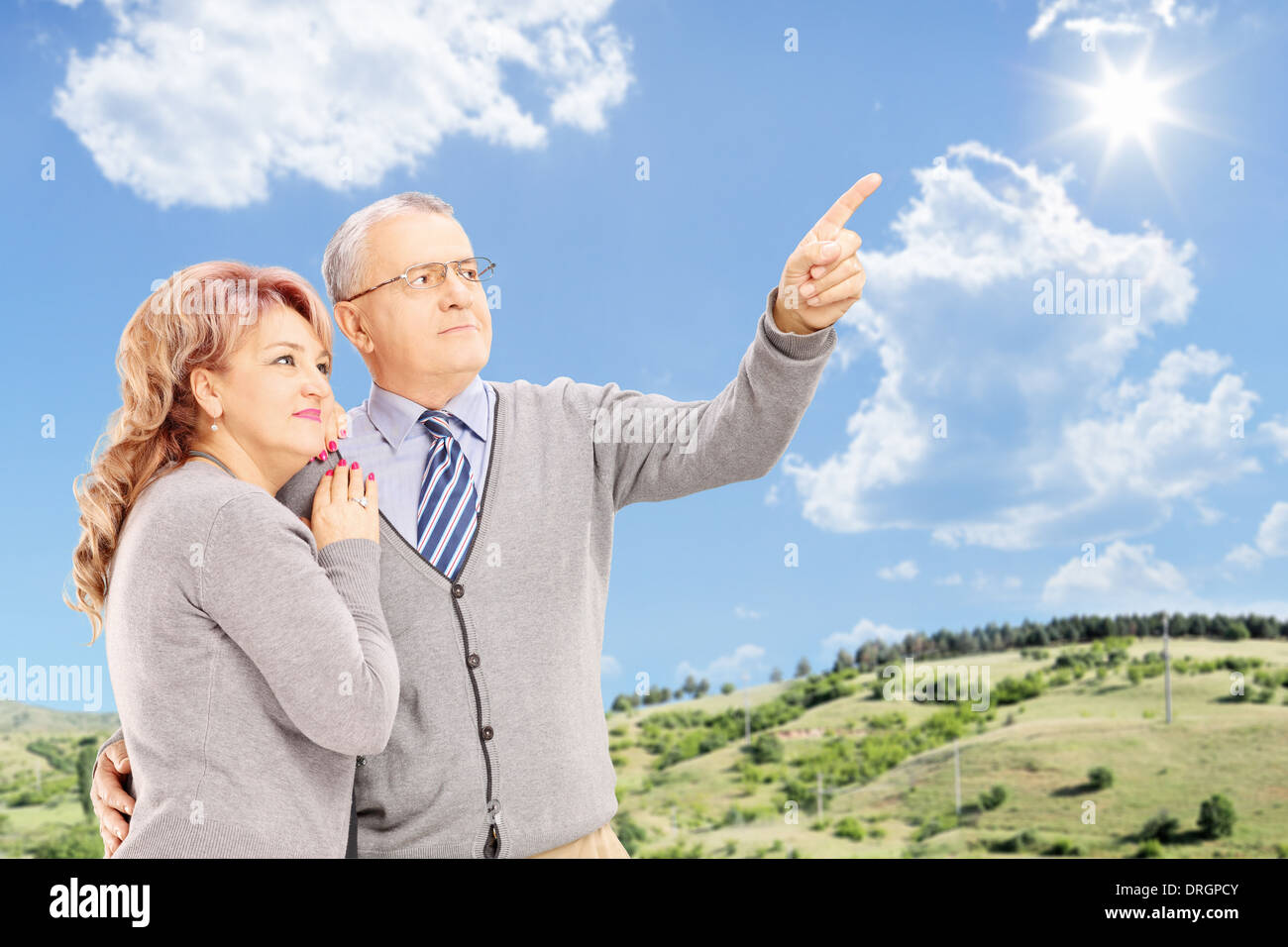 Mature couple standing close together and looking, with blue sky in the background Stock Photo