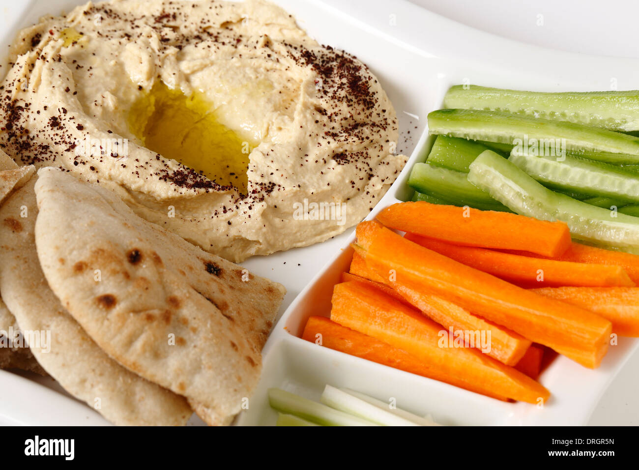 A dip tray with hummus, bread, carrot sticks, celery and cucumber Stock
