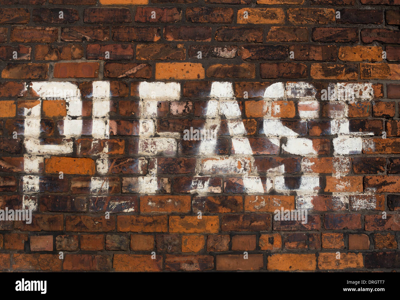 'Please' written on a brick wall with white paint Stock Photo