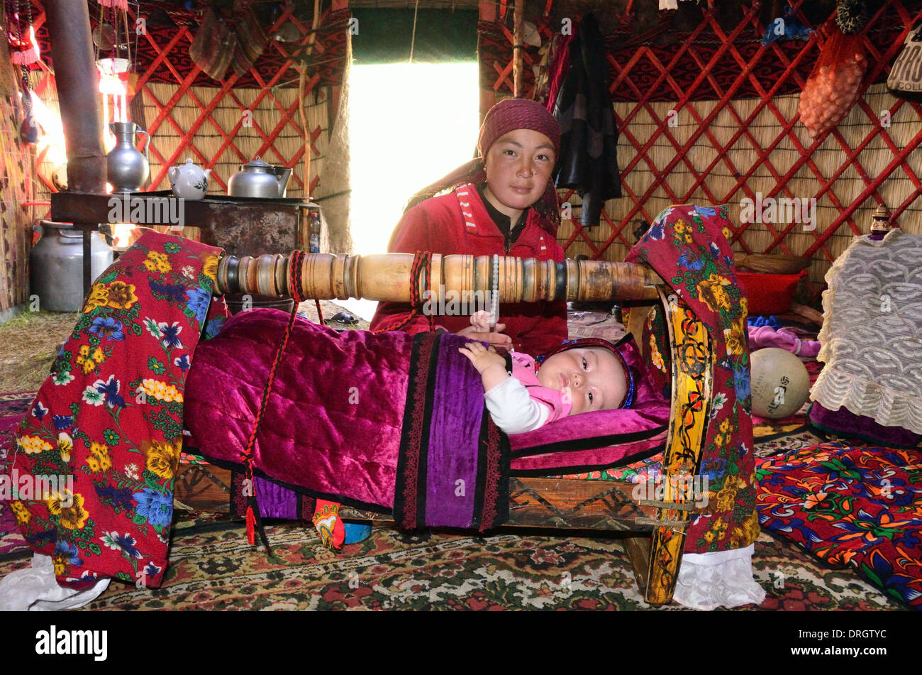 Kyrgyz mother with her child in a cradle inside a yurt in the mountains of southern Kyrgyztan Stock Photo