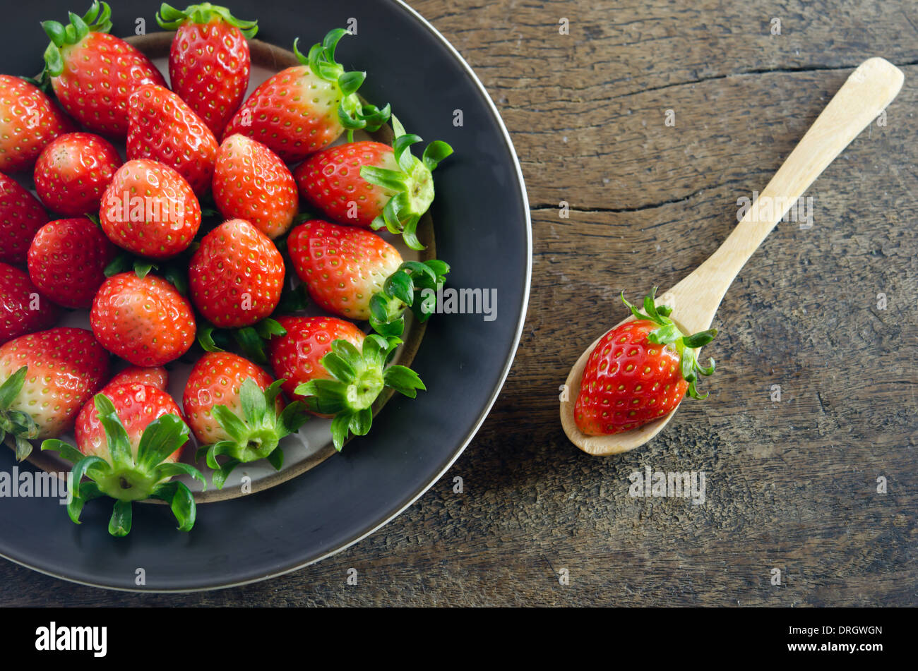 still life of fresh red strawberries on dish over wooden background ...