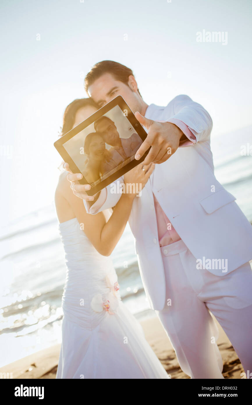 Brautpaar mit Ipad am Strand auf Ibiza, Spanien - bridal couple at the Beach, Ibiza, Spain Stock Photo