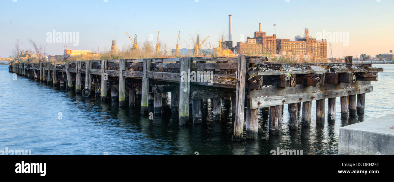 An old pier in Baltimore Inner Harbor set against a backdrop of the iconic Domino Sugars Factory Stock Photo