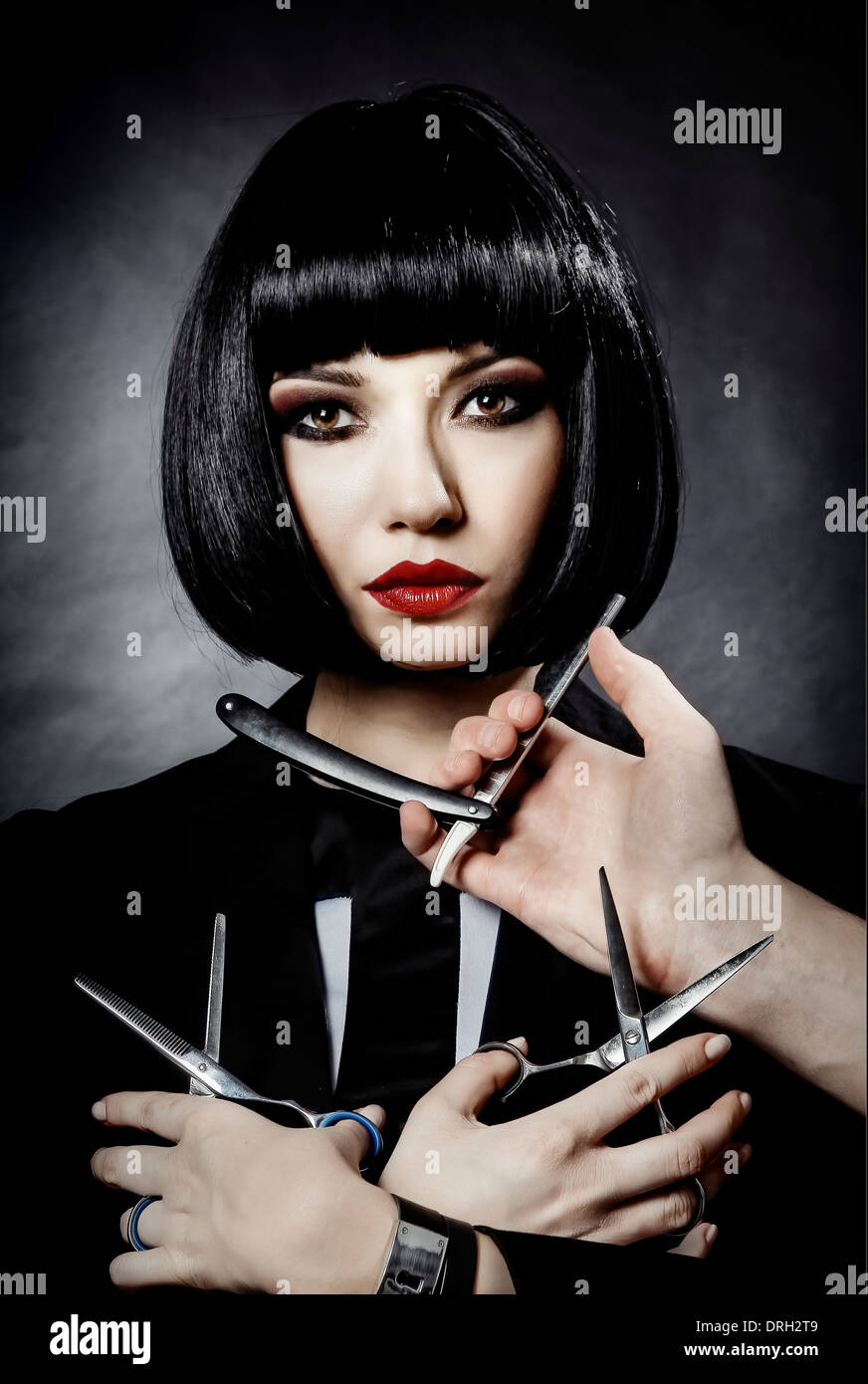 Conceptual hairstylist portrait black hair woman scissors and razor Stock Photo