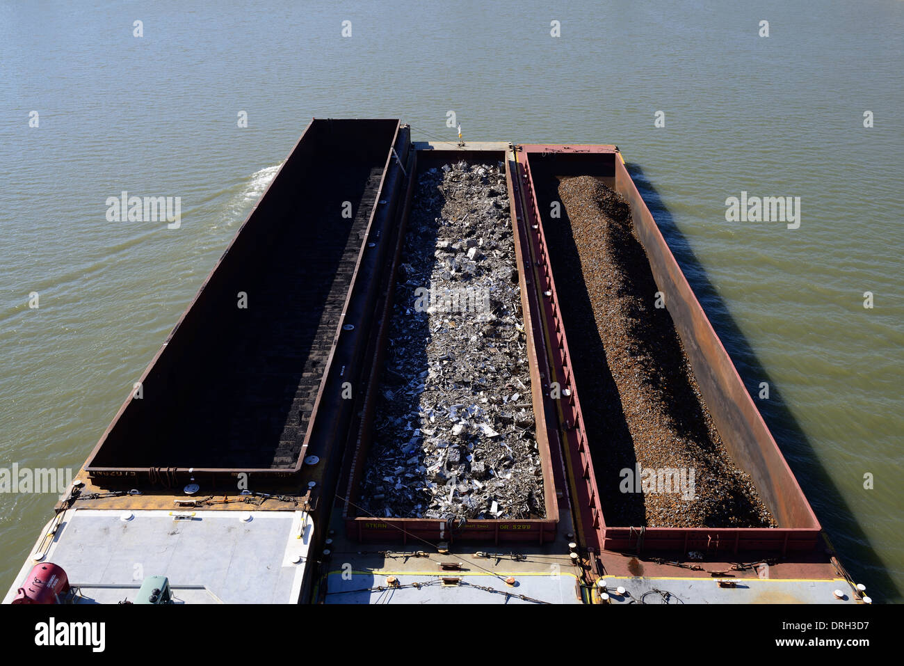 A river barge on the Ohio River with loads of coal, scrap metal and iron and more on a sunny day. Stock Photo