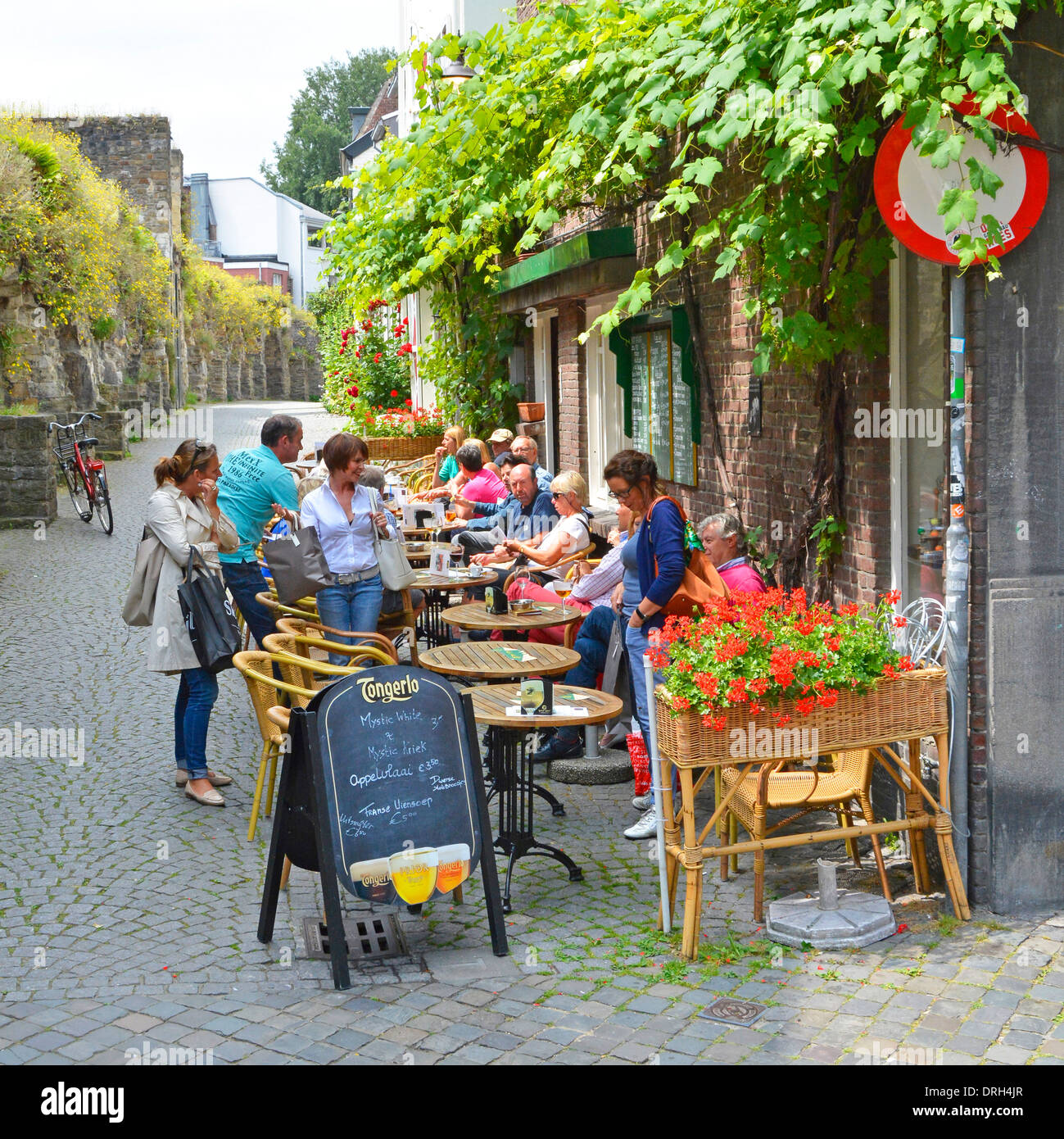 Maastricht pavement cafe bar tourists & locals enjoying refreshments sitting outdoor tables in pretty Dutch side street summer Limburg Netherlands EU Stock Photo