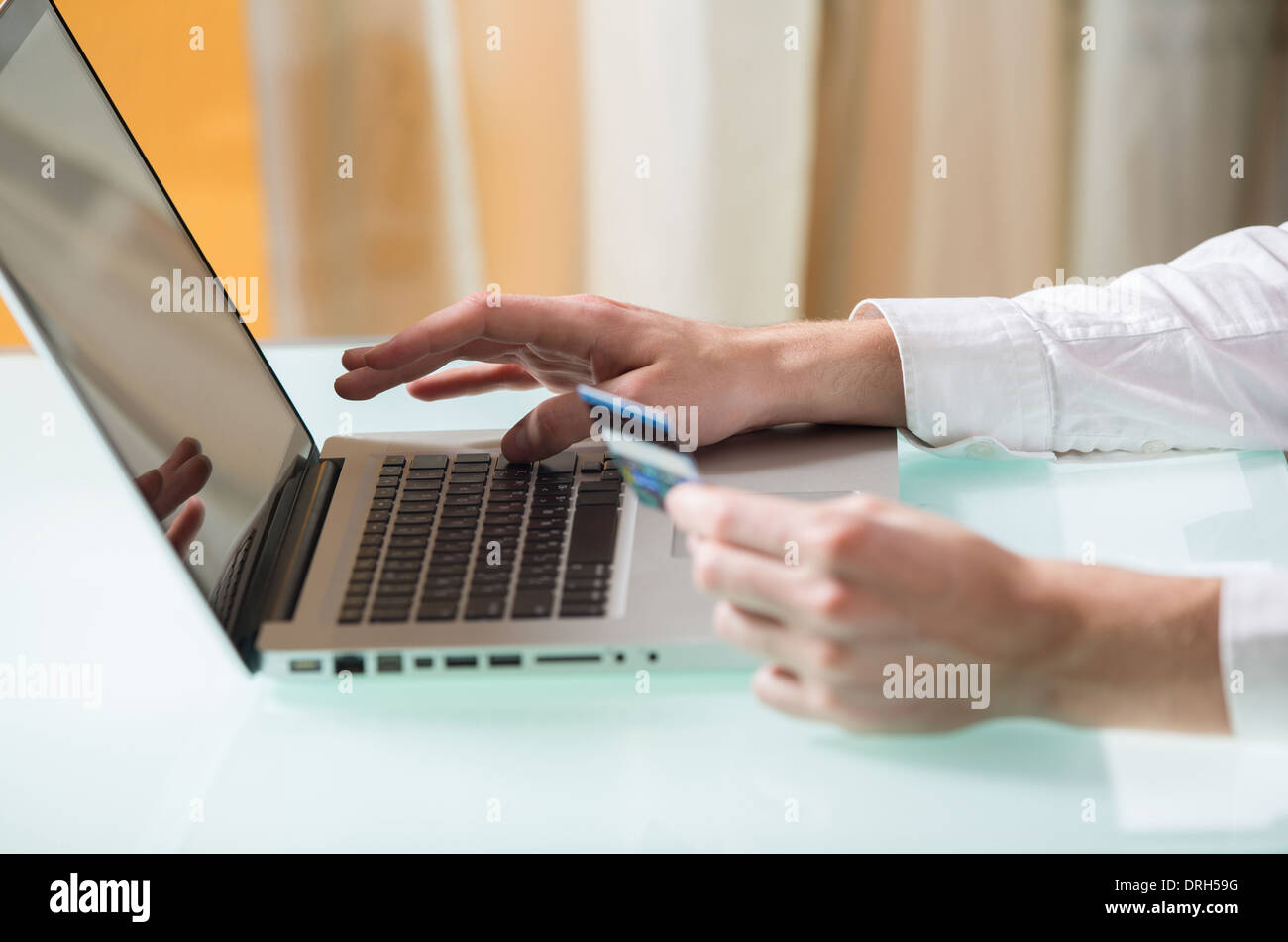 Man's online banking payment shopping card credit money internet business computer while holding a credit card in the other hand Stock Photo