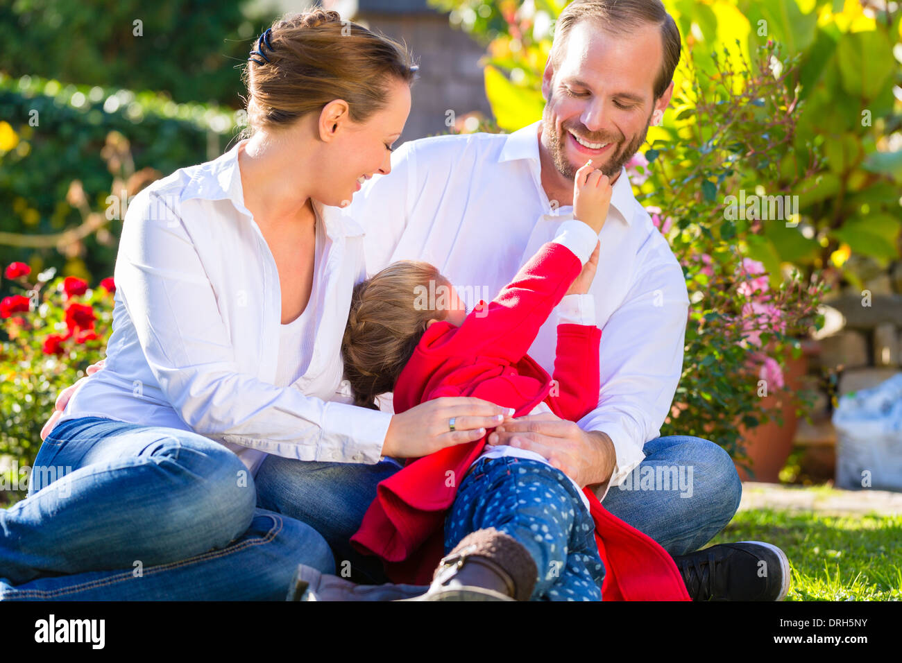 Family with mother, father and daughter together in the garden meadow Stock Photo