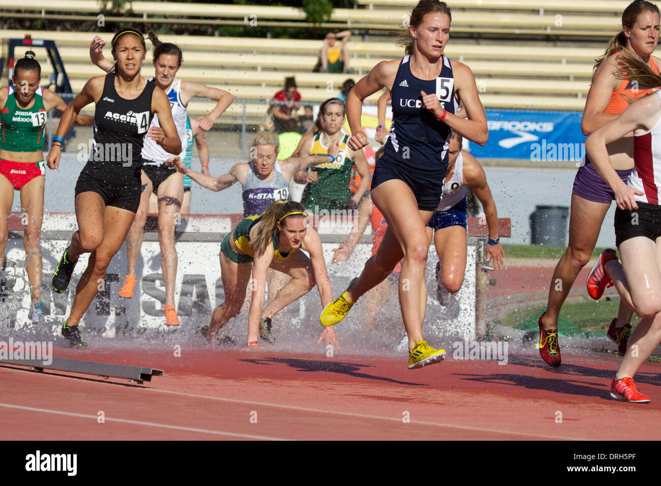 Female athletes at the water jump during a steeplechase race at an American track and field meet in California Stock Photo