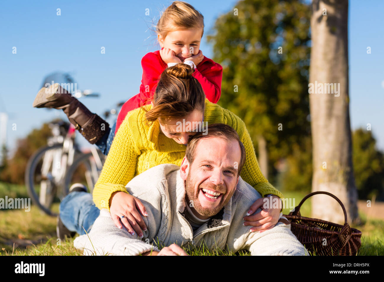 Family with mother, father and daughter having break on family trip with bicycle or cycle in park Stock Photo