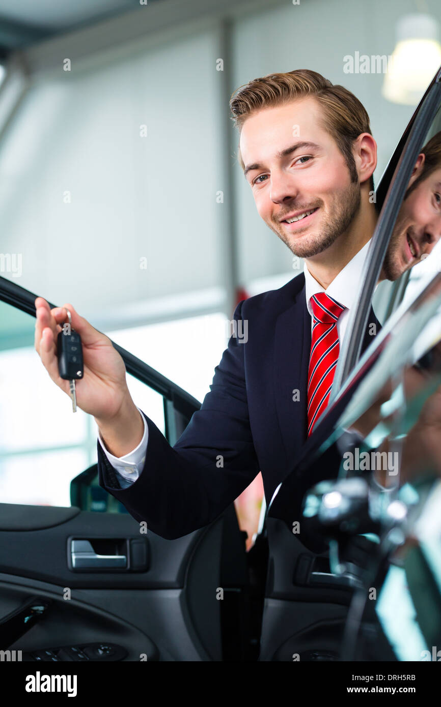 Seller Or Car Salesman In Car Dealership With Key Presenting His New And Used Cars In The Showroom Stock Photo Alamy